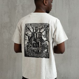 Uomo di spalle con t-shirt grigio chiaro e grande stampa nera in stile xilografia che raffigura figure in giacca e cravatta con testo italiano sulla comodità del governo