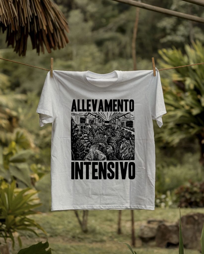 T-shirt bianca streetwear con stampa nera realizzata ad incisione xilografica raffigurante una folla stipata in un vagone della metropolitana e testo ‘Allevamento Intensivo’, appesa a un filo con sfondo naturale verde.